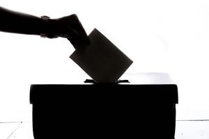 sillohette of hand putting a voting slip in a ballot box